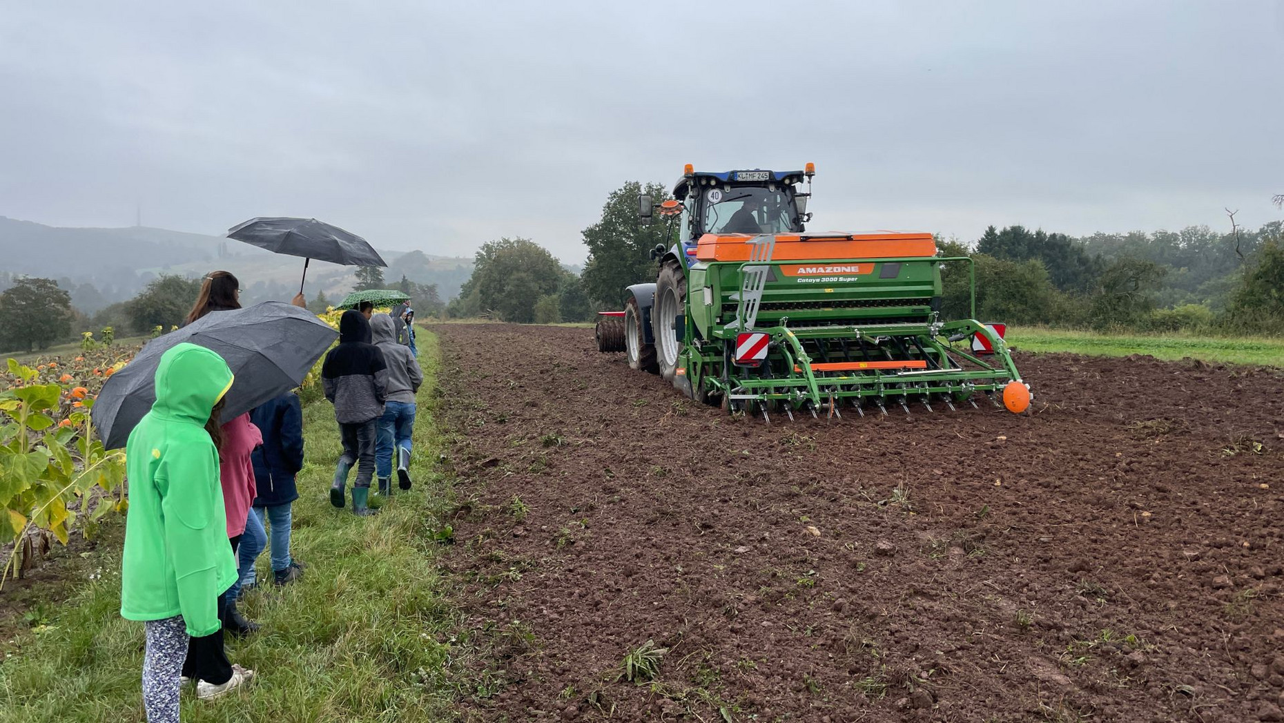 Kinder auf dem Feld mit Traktor.