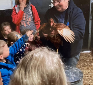 Sabine Nussbaum mit Huhn im Arm und Kindern.