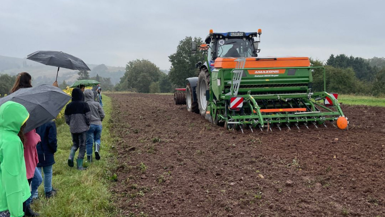 Kinder auf dem Feld mit Traktor.